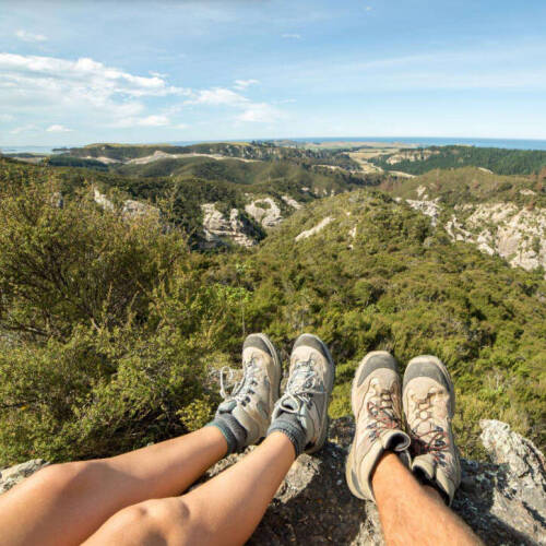 2 hikers legs and feet in the foreground of a scenic mountain vista